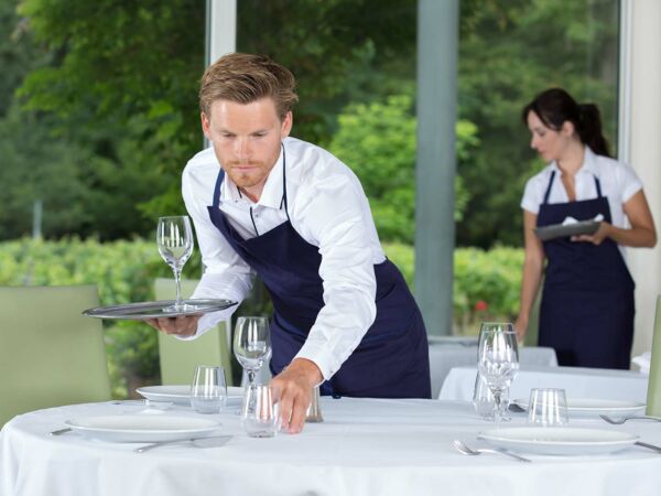 Mann richtet den Tisch her